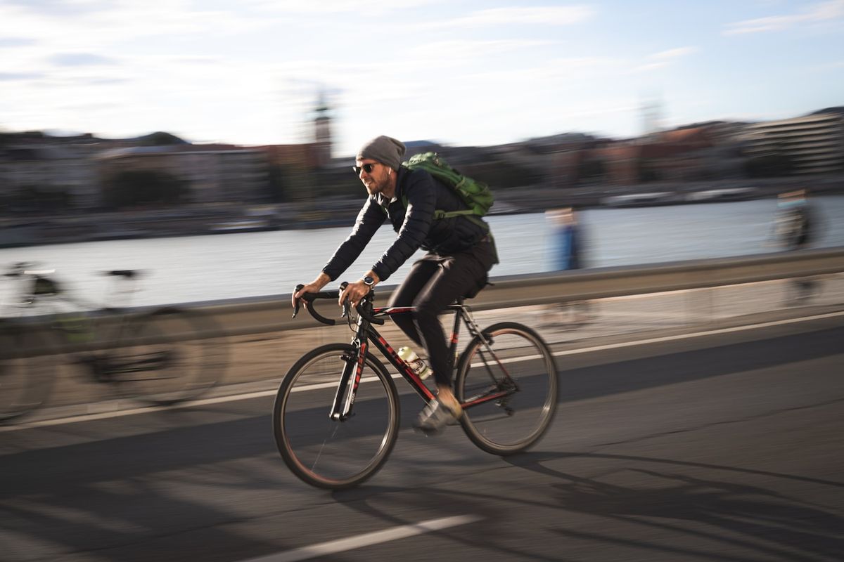 Cyklist pendler over en bro i en by i morgenlys