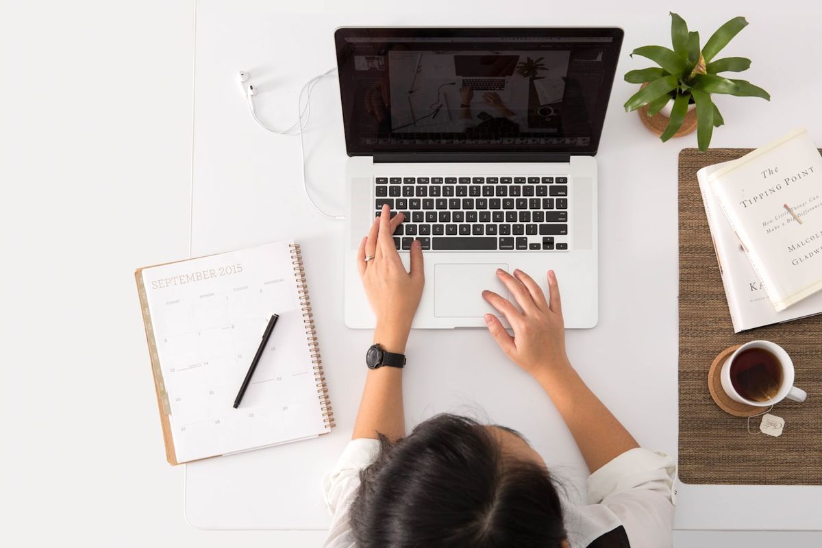Overblik over et skrivebord med baerbar computer, kalender og kaffe